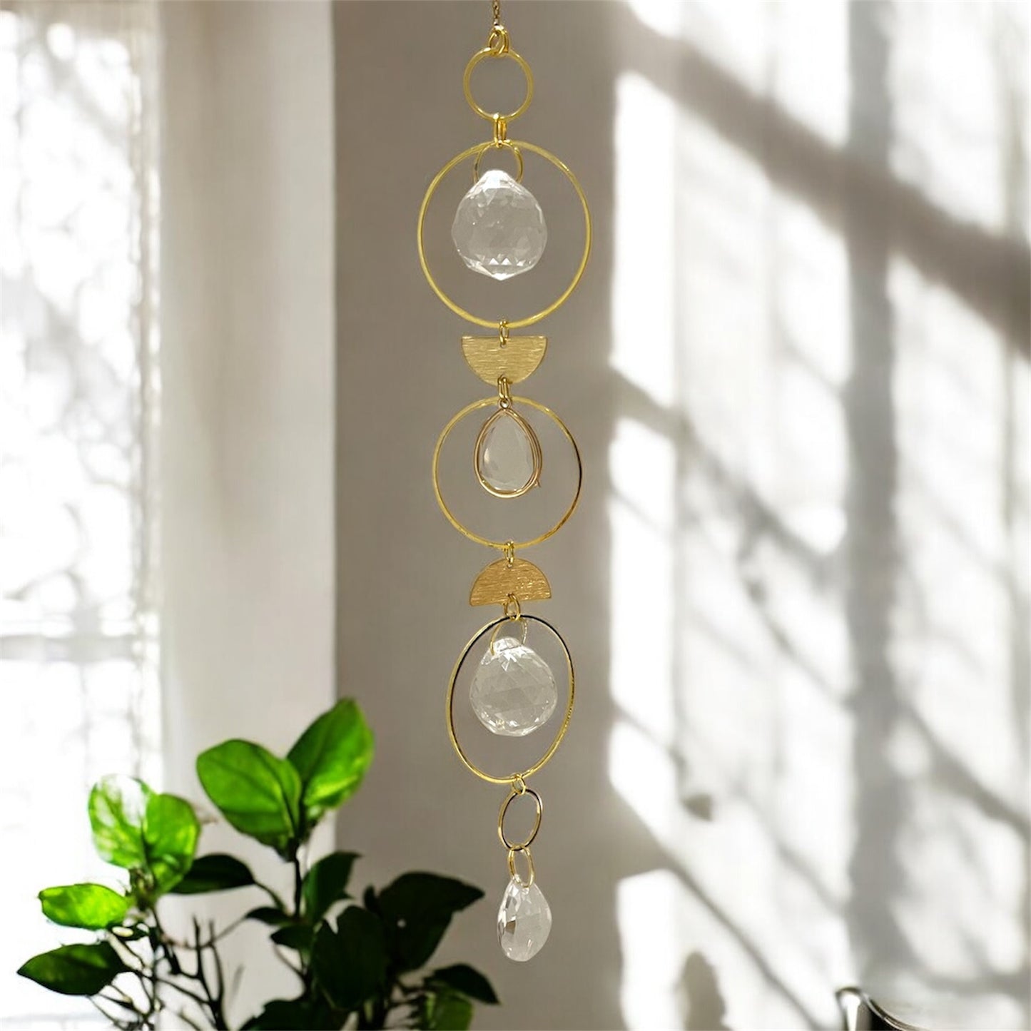 Decorative hanging with gold loops and clear crystals against a light background