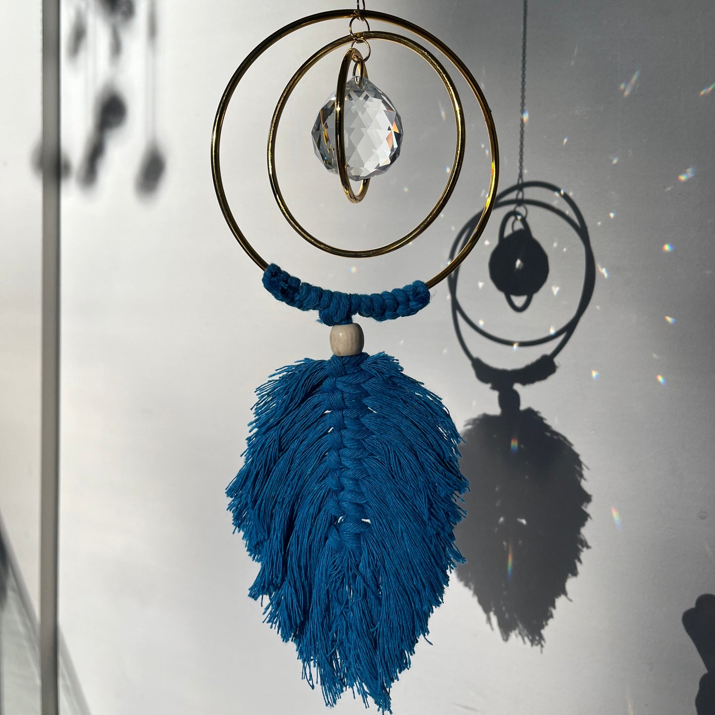 Decorative hanging with blue tassel and gold circular design on a white background