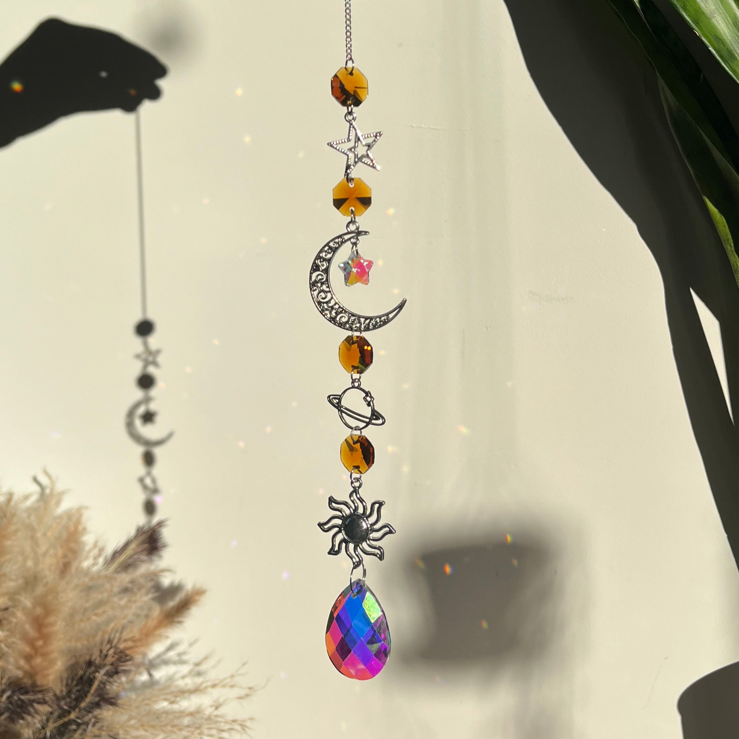 Decorative hanging ornament with celestial elements and a colorful teardrop pendant.