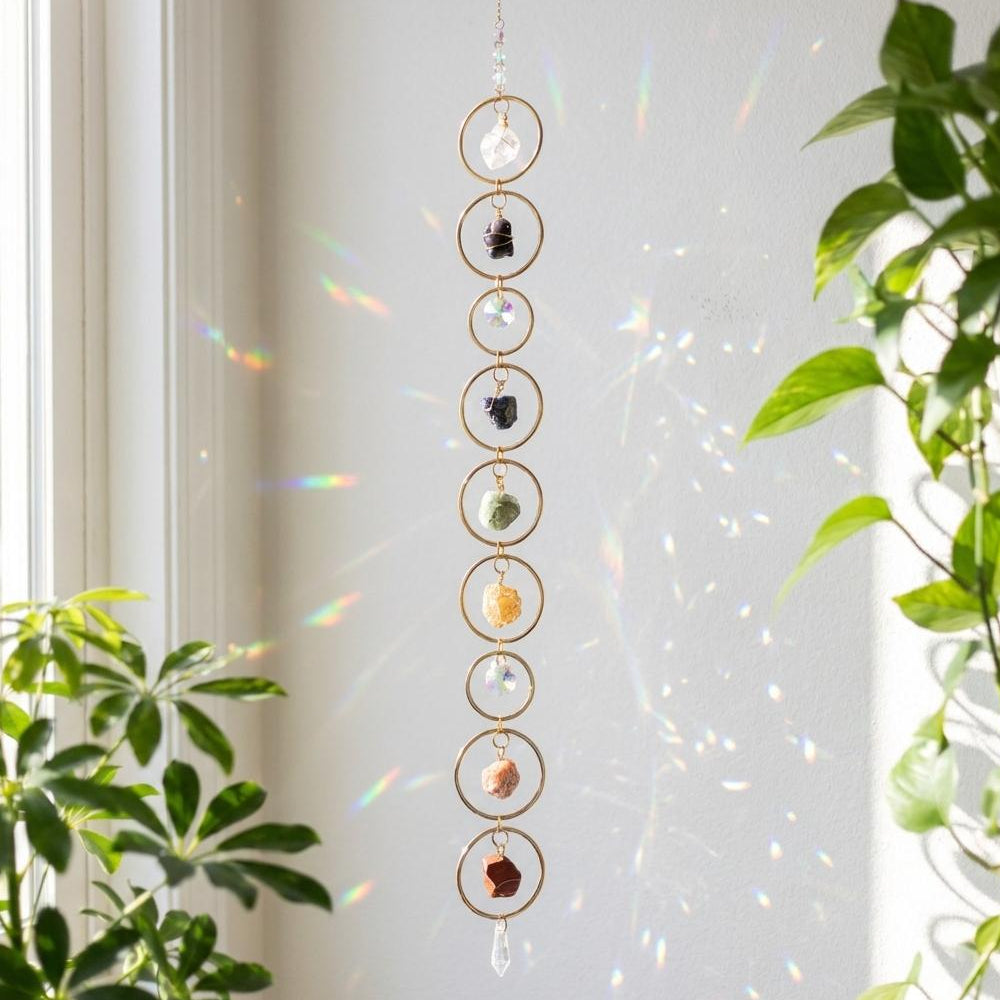 Decorative hanging with crystals and stones in front of a window with plants.