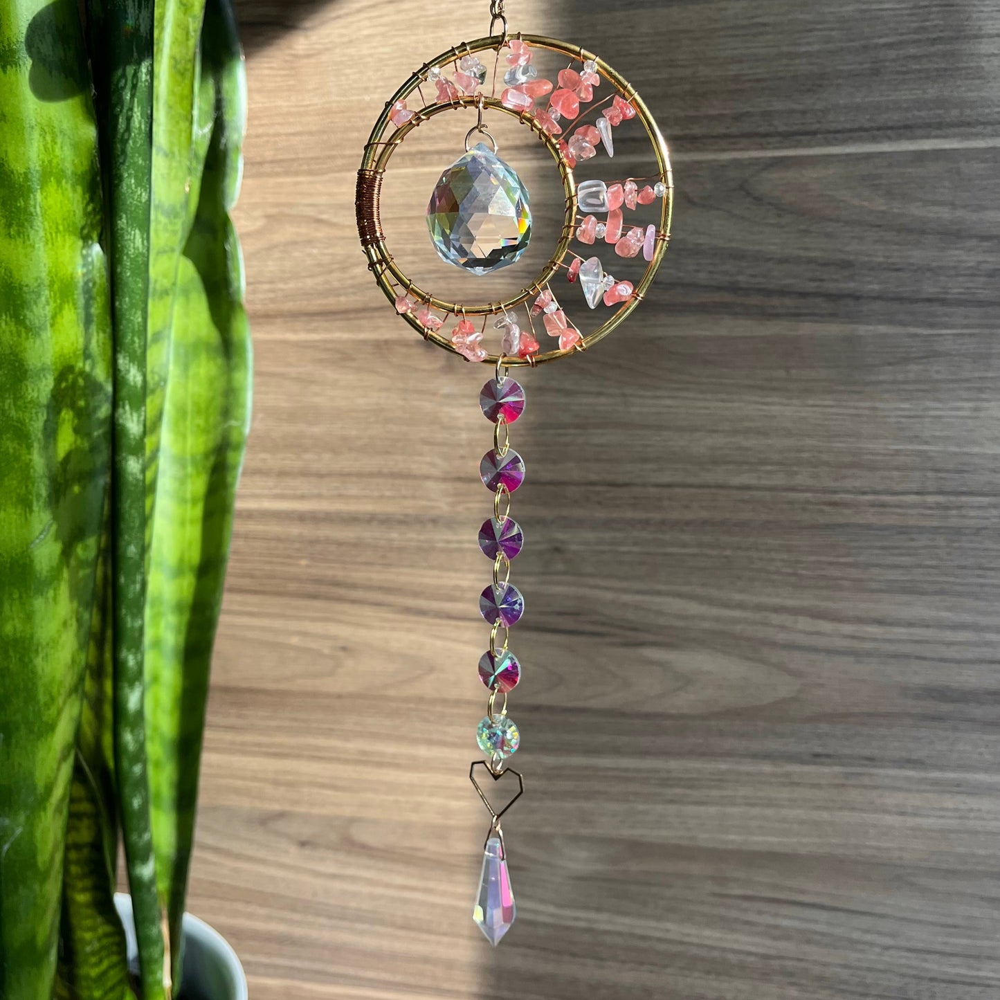 Decorative crystal hanging on a wooden surface next to a potted plant