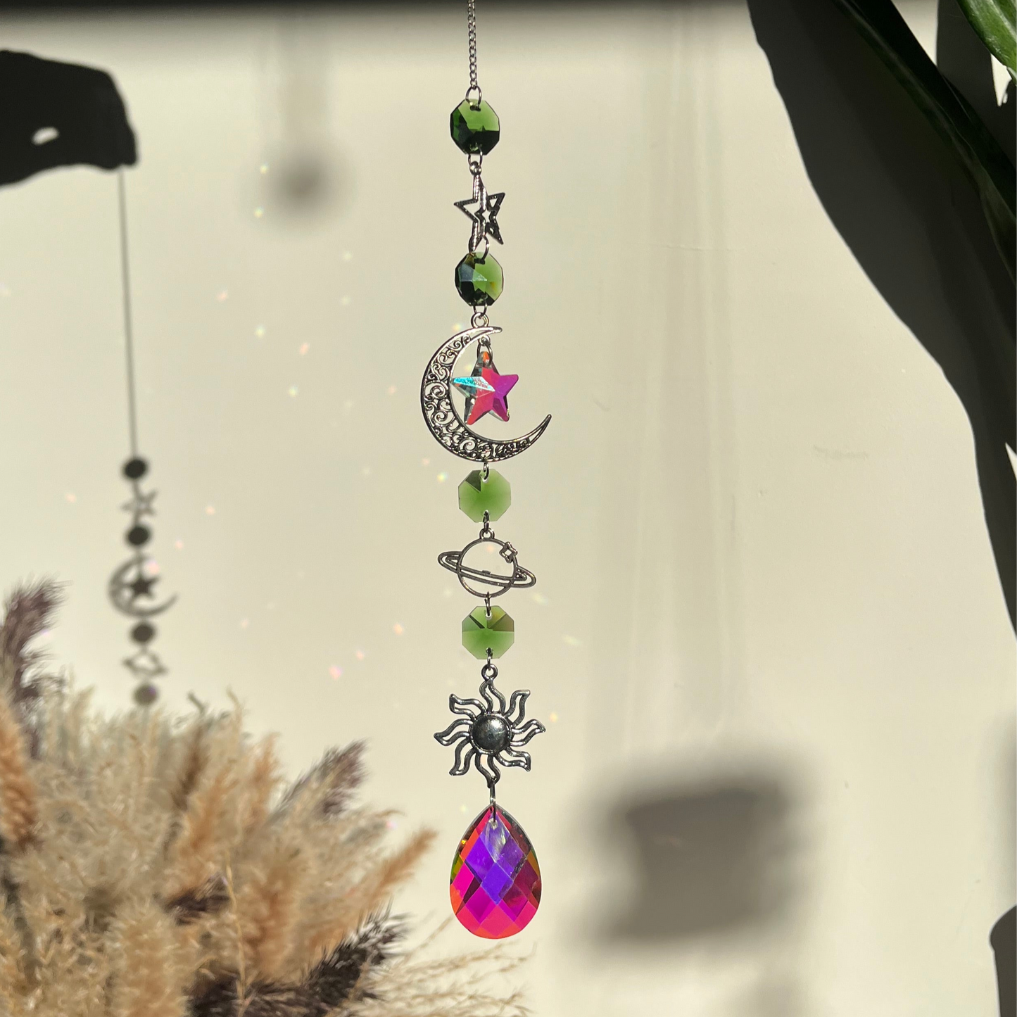 Decorative hanging ornament with celestial elements and a colorful teardrop pendant.