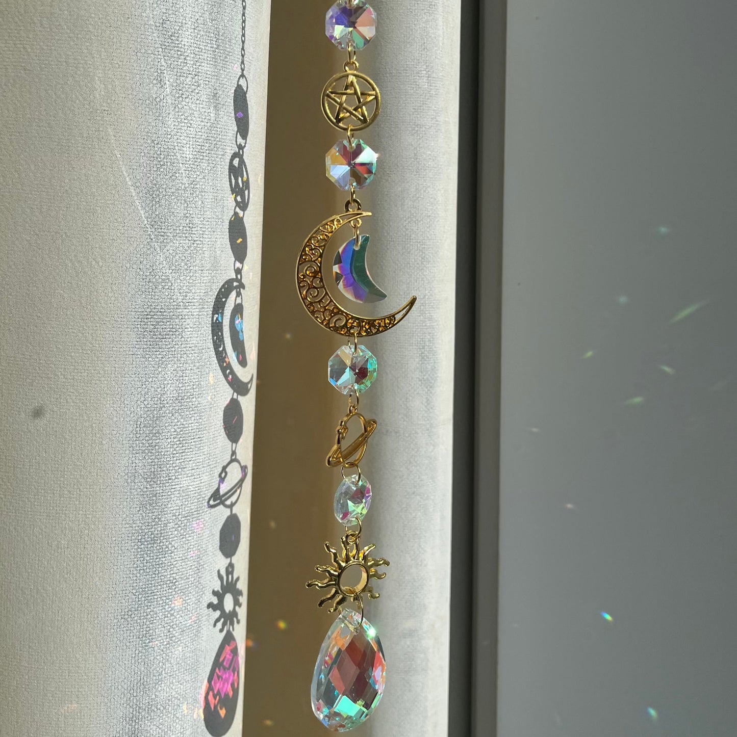 Decorative hanging charm with celestial elements on a plain background
