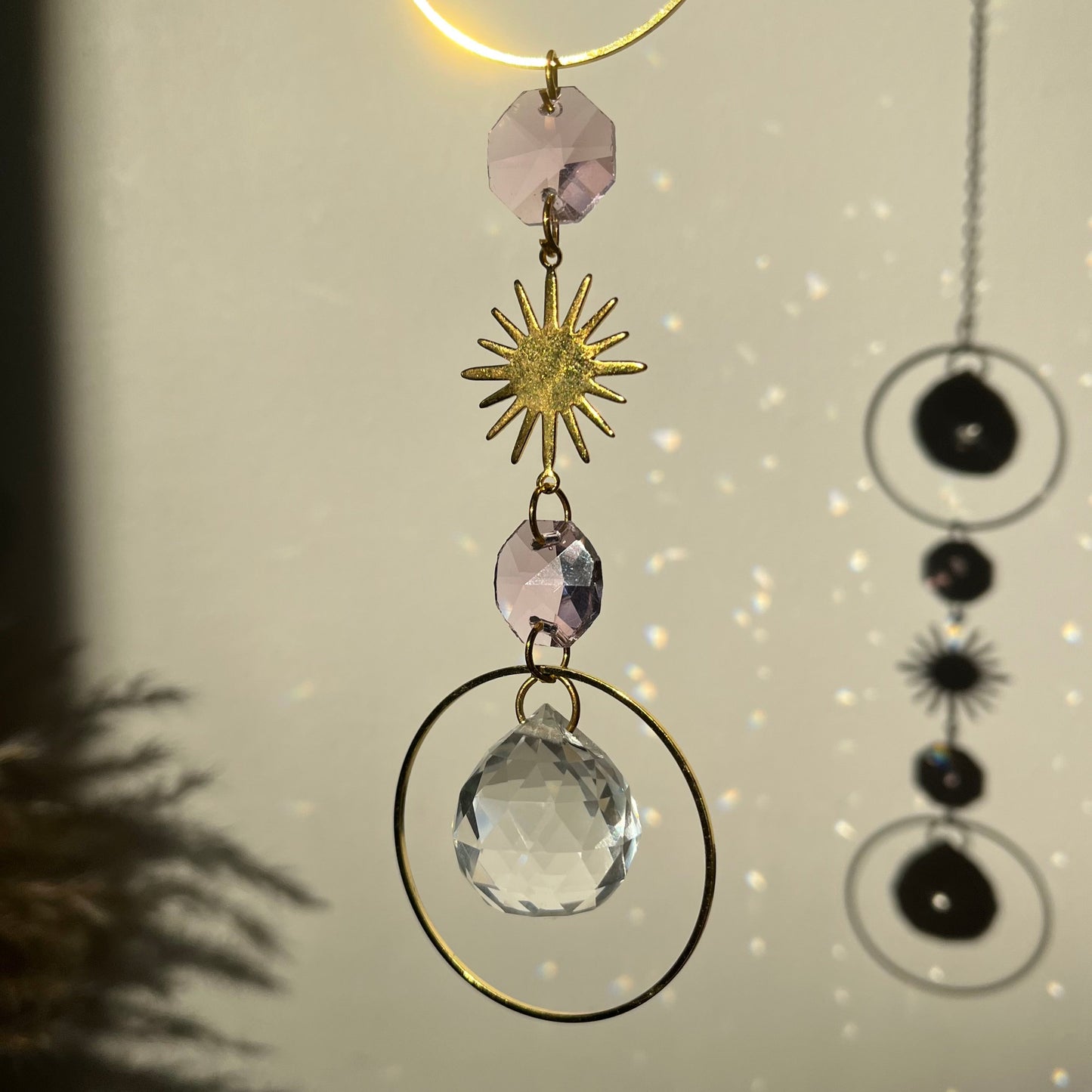 Decorative hanging with crystals and sun design on a neutral background