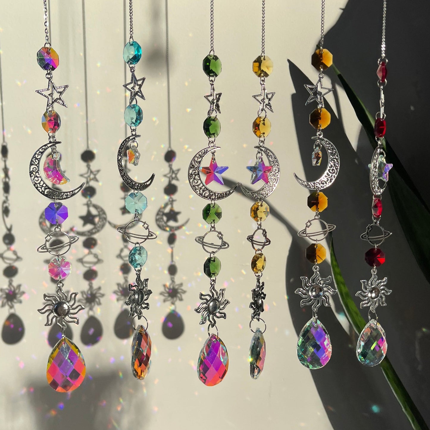 A series of decorative wind chimes with colorful gemstone pendants and silver elements, displayed against a light background.