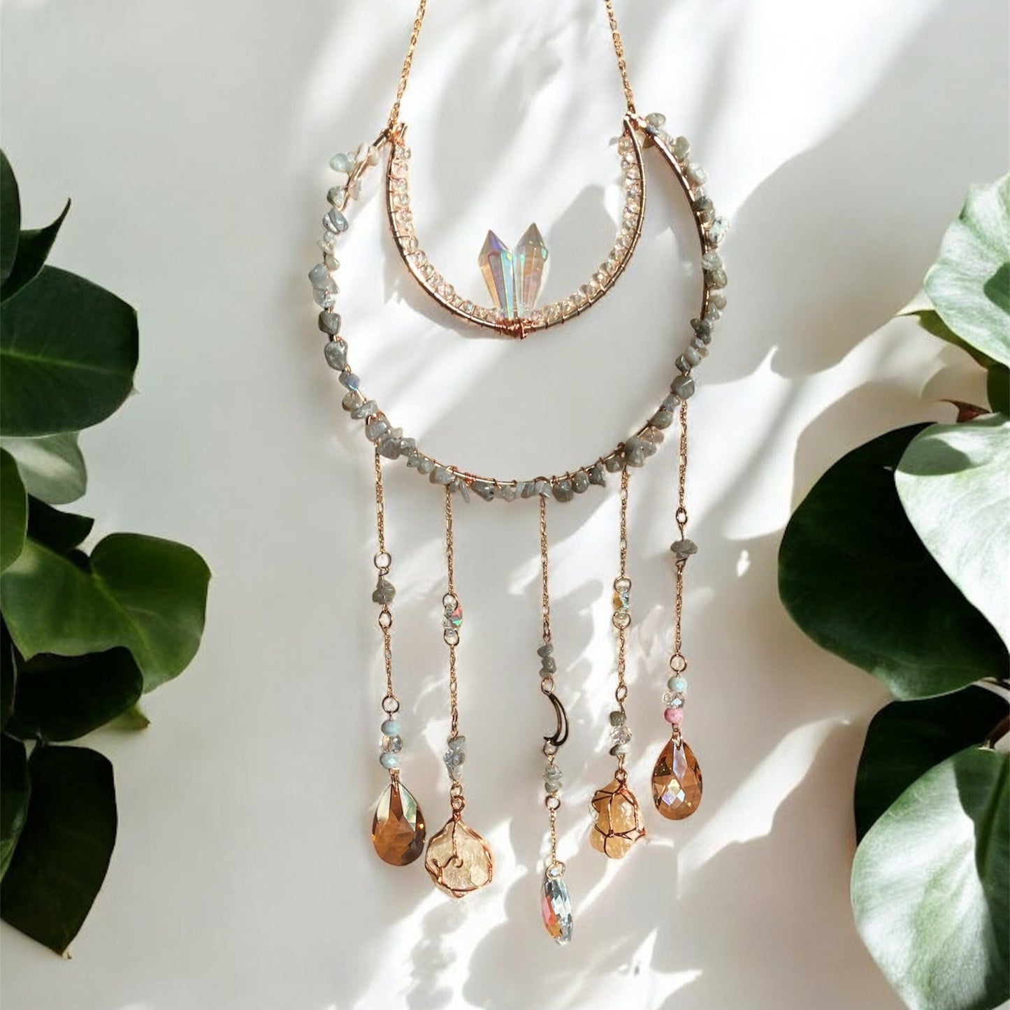 Suncatcher with gemstones and crystals on a white background with green leaves