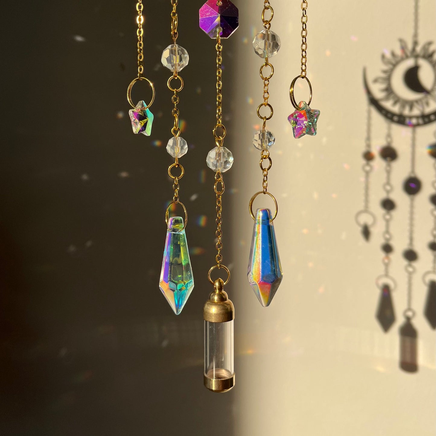 Decorative hanging chains with crystals and a small gold pendant on a dark background.