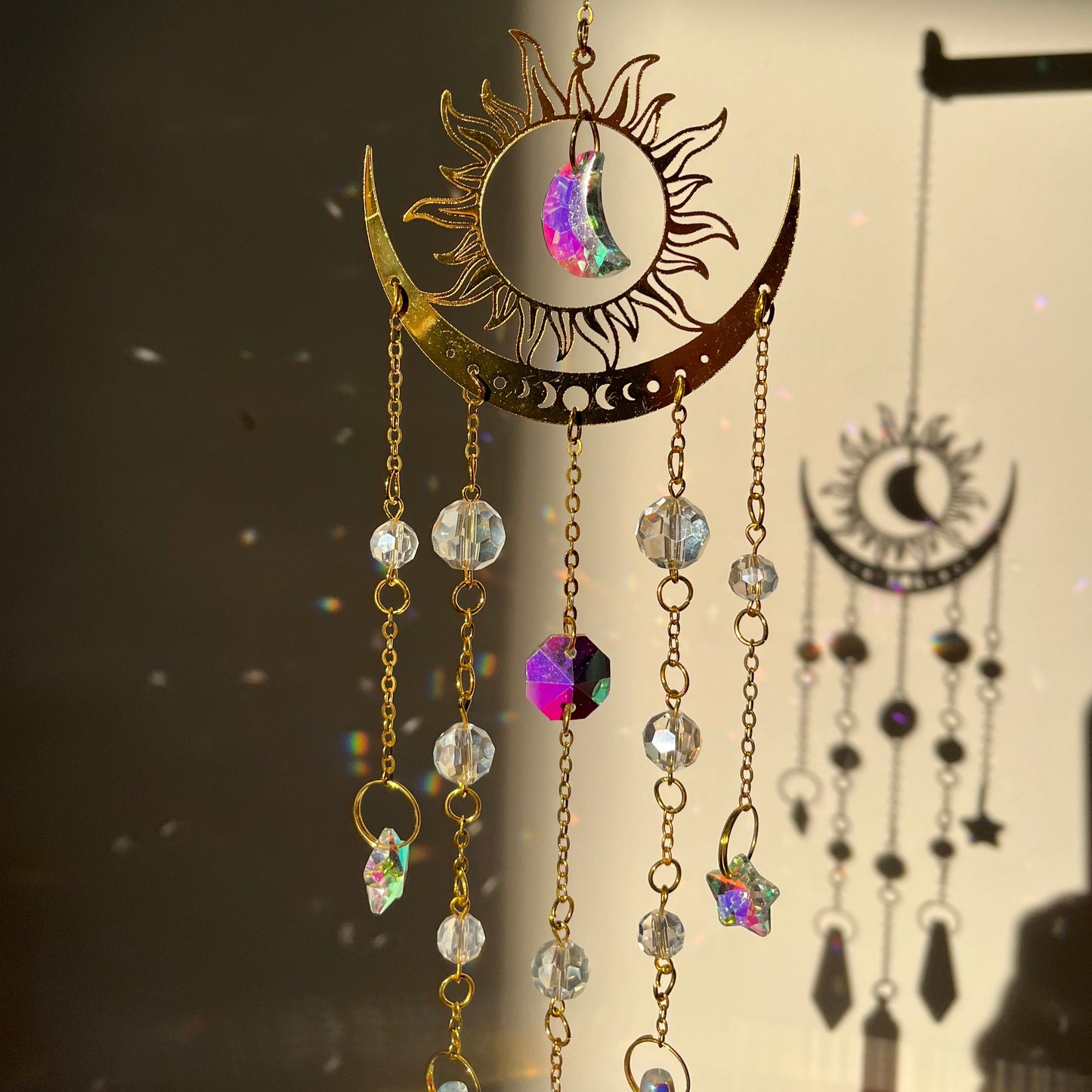 Suncatcher with sun and moon design and colorful beads on a dark background