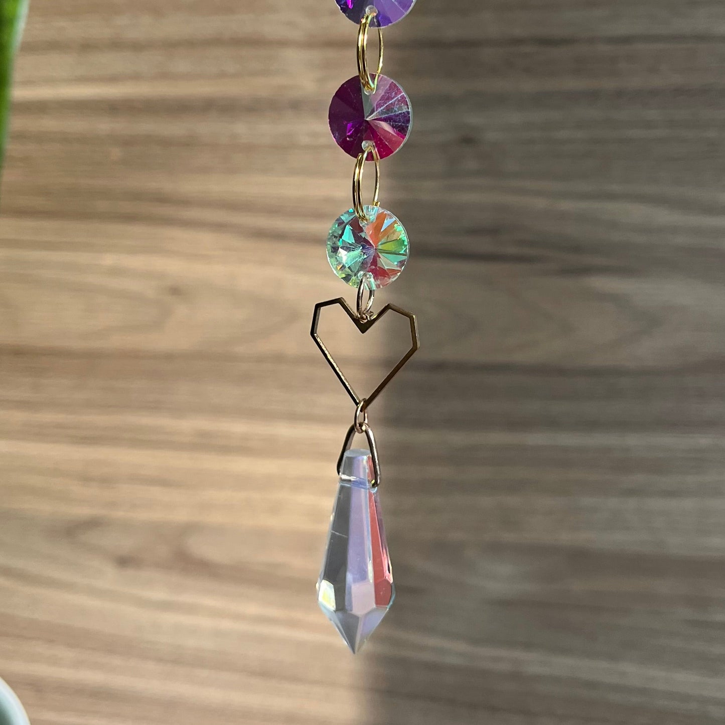 Decorative hanging crystal with colorful beads on a wooden surface