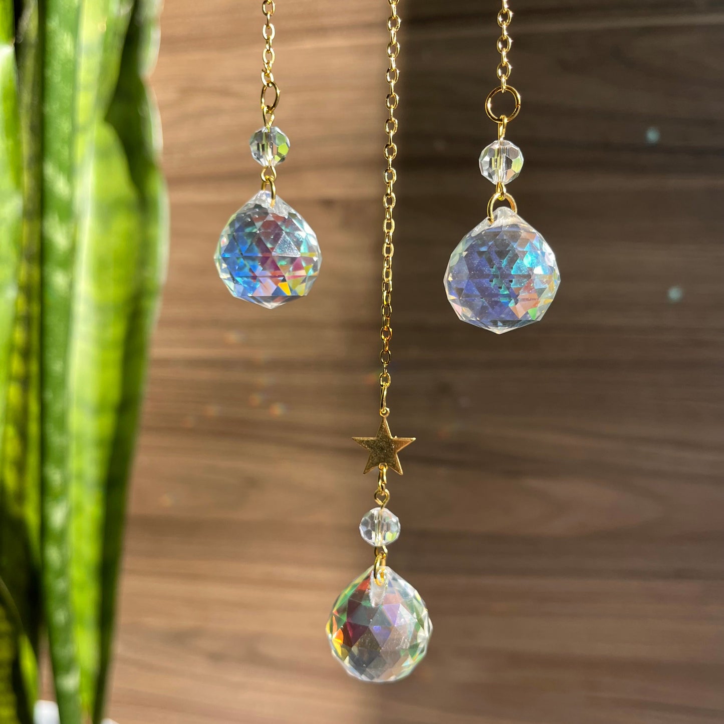 Pair of dangling earrings with crystal-like beads on a wooden surface.