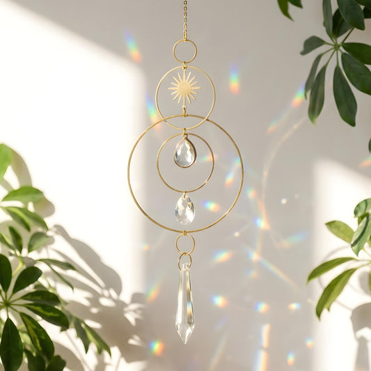 Decorative hanging crystal with sun design in front of a plant