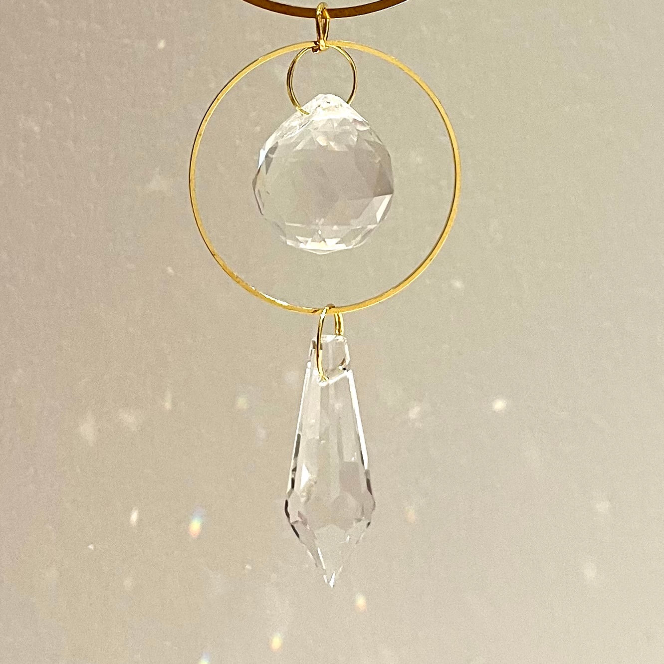 Crystal hanging ornament with gold ring on a light gray background