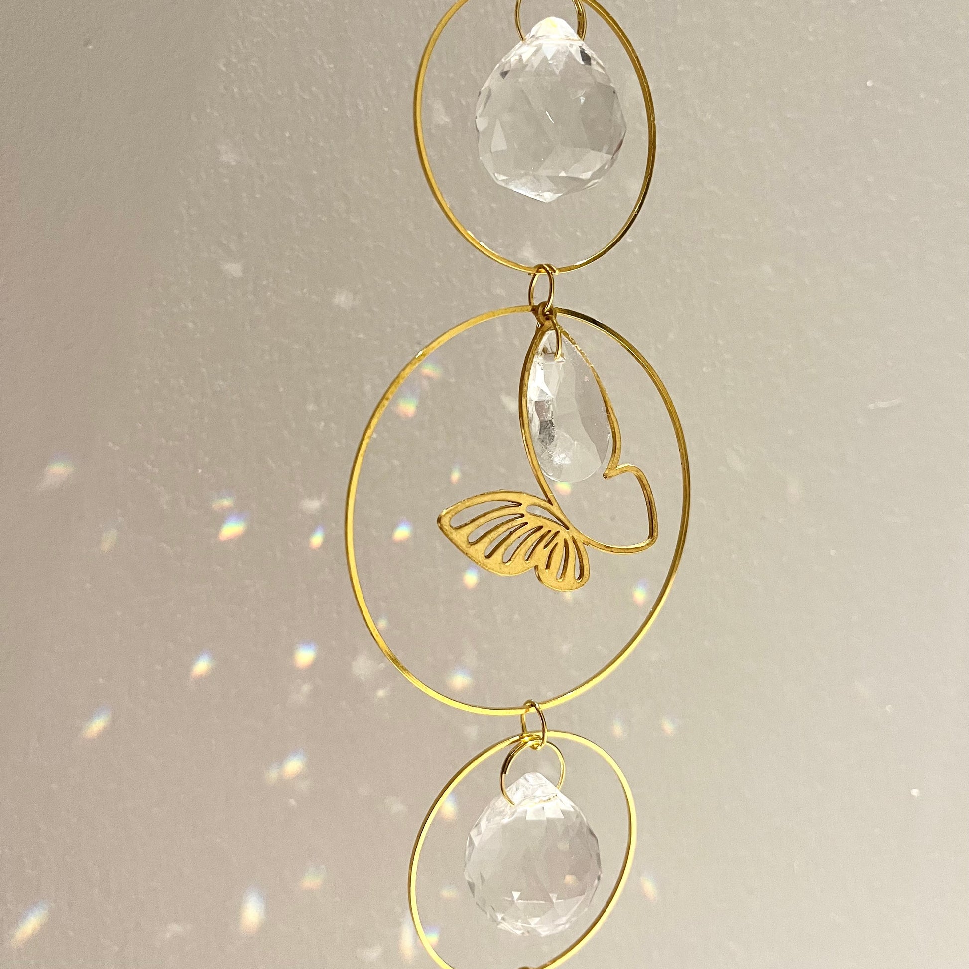 Decorative hanging ornament with gold loops and clear crystals on a light background