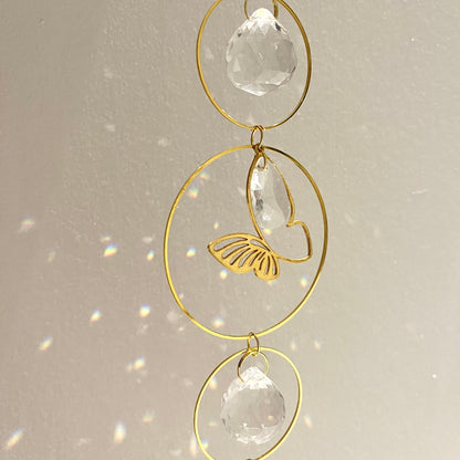 Decorative hanging ornament with gold loops and clear crystals on a light background