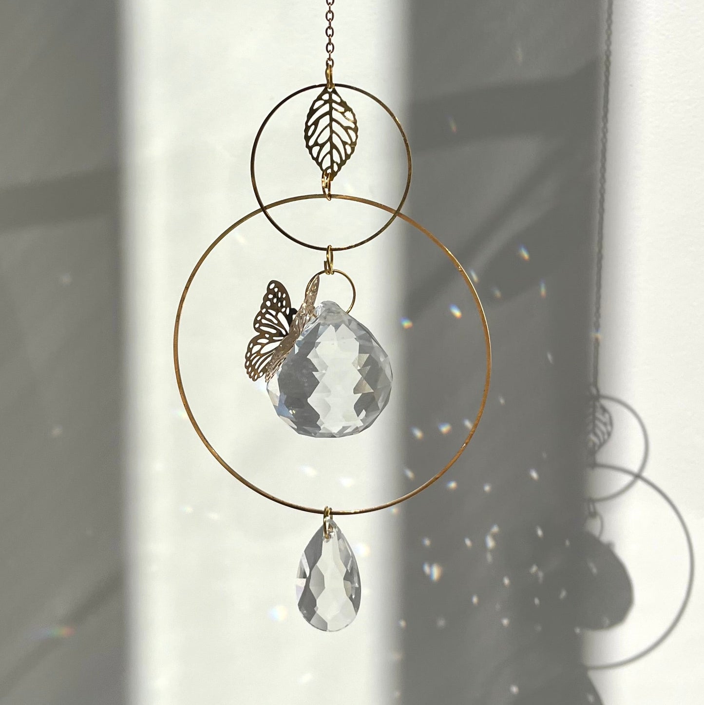 Decorative hanging crystal with butterfly and leaf design against a light background