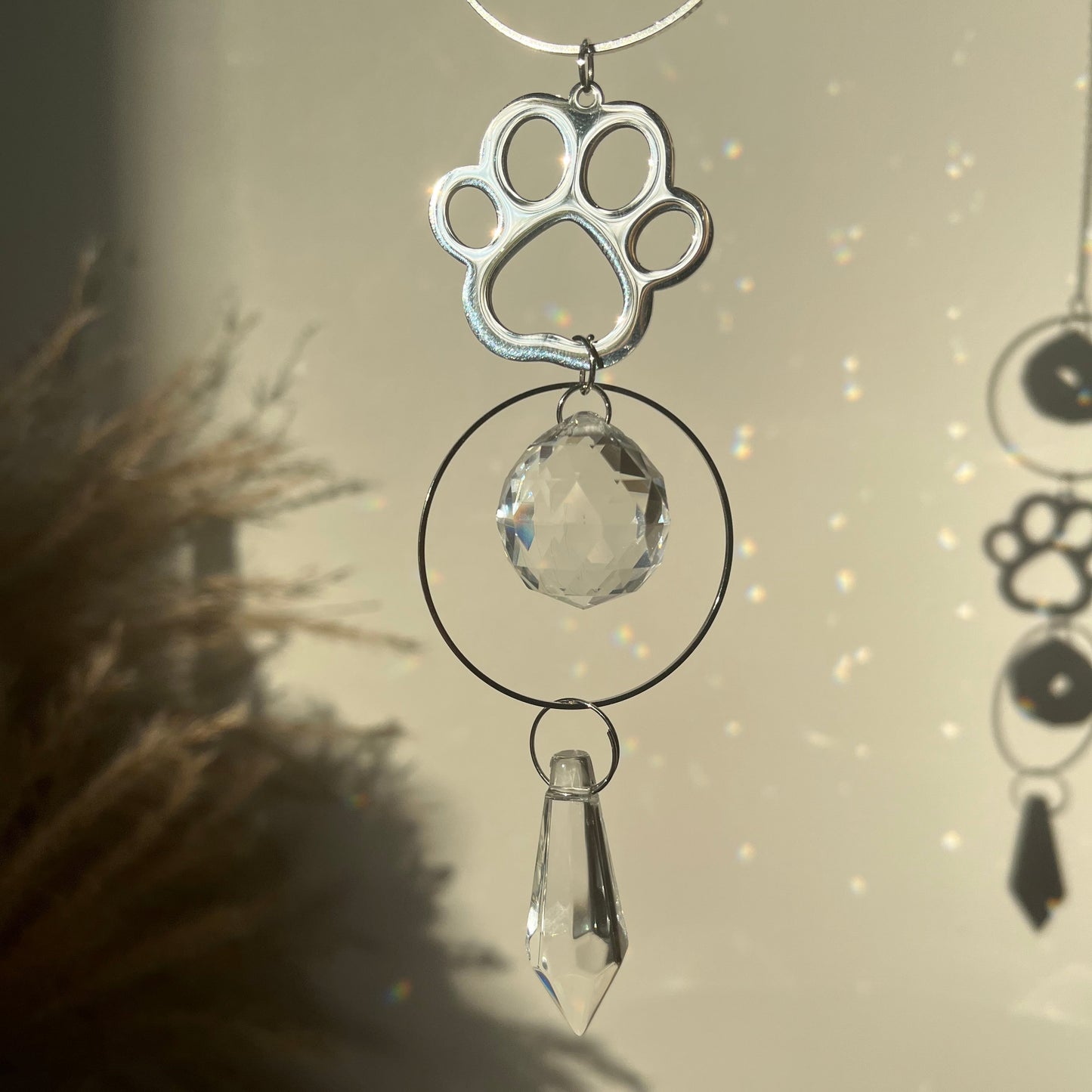 Decorative hanging with paw print and crystal design against a neutral background