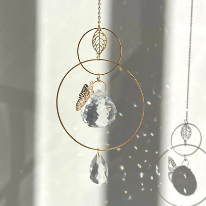 Decorative hanging crystal with gold chain and leaf charm against a light background