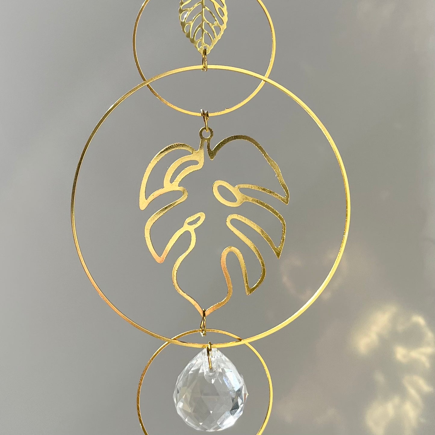 Decorative gold leaf design with a clear crystal on a gray background