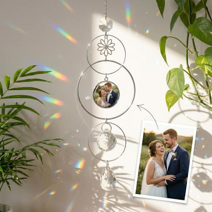 Decorative hanging ornament with photos of a couple, surrounded by plants.