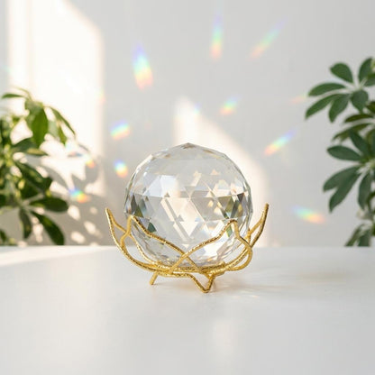 Clear crystal ball on a gold stand with a blurred plant background