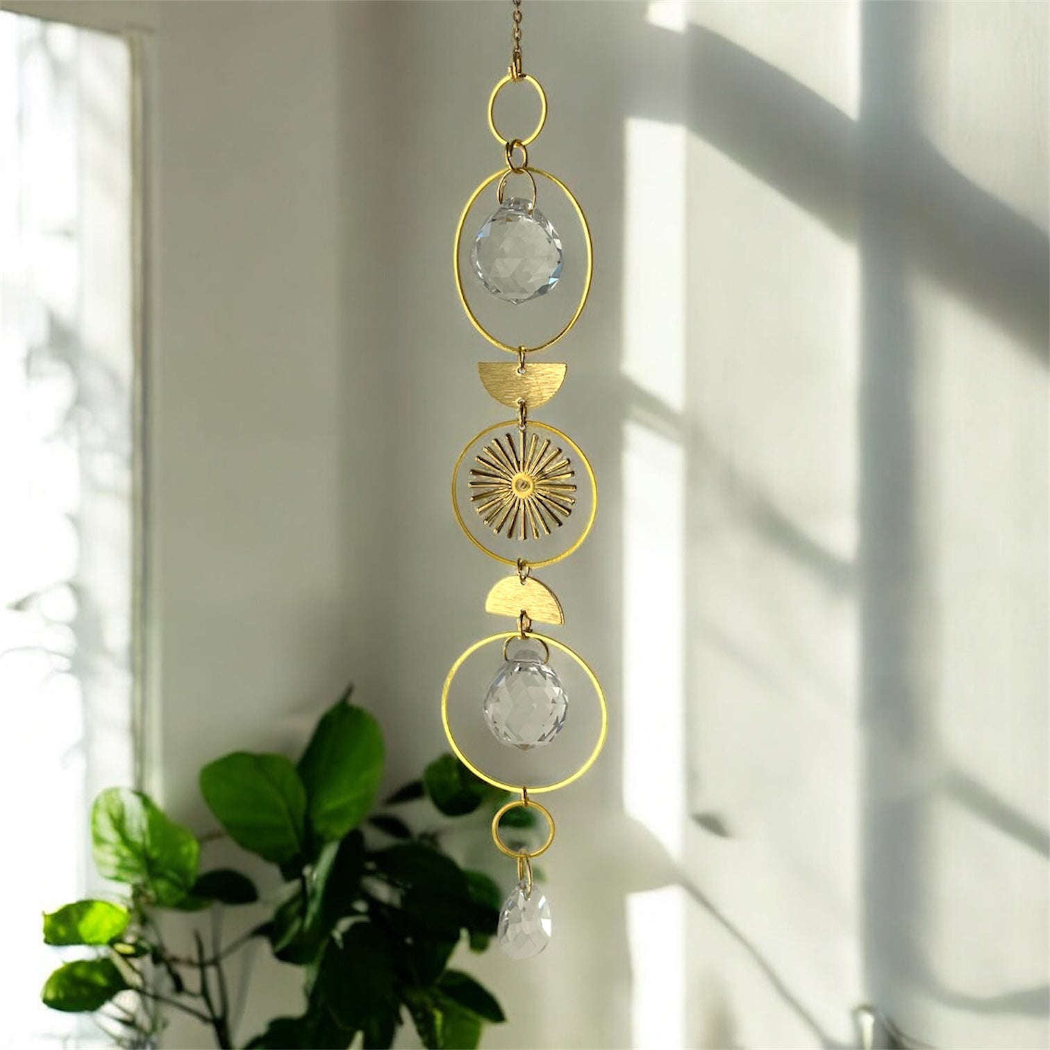 Decorative hanging crystal with gold accents in a bright room with sunlight filtering through.
