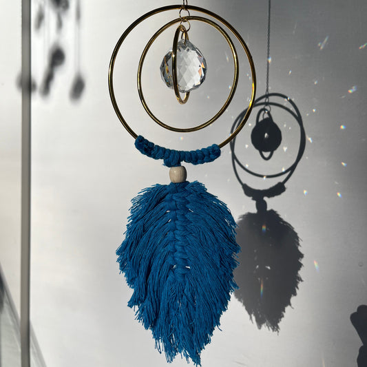 Decorative hanging with blue tassel and gold circular design on a white background