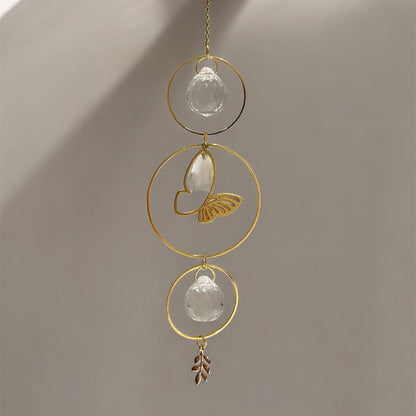 Decorative hanging ornament with gold loops and crystal-like elements on a neutral background