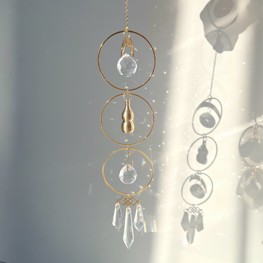 Decorative hanging crystal and gold chain against a light gray background