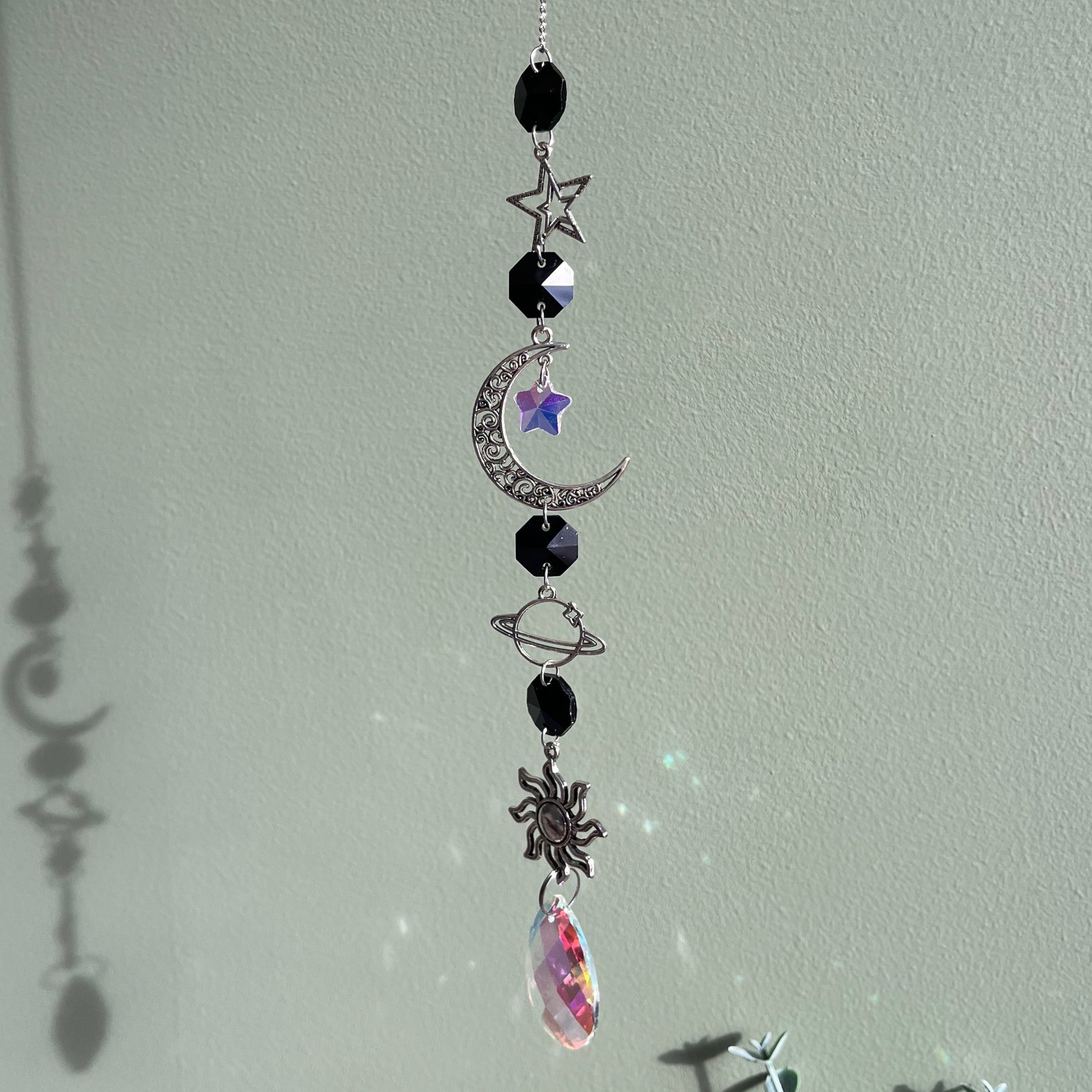 Decorative hanging charm with celestial elements on a light gray background
