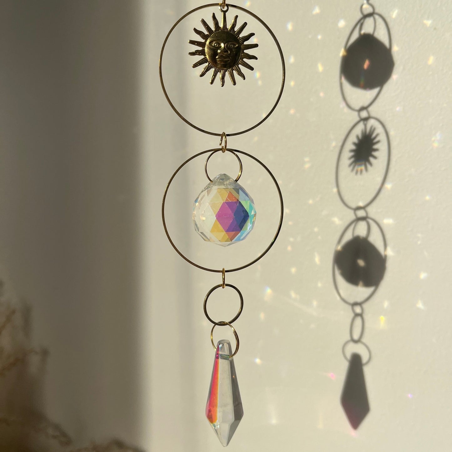 Decorative hanging with geometric shapes and crystals against a light background