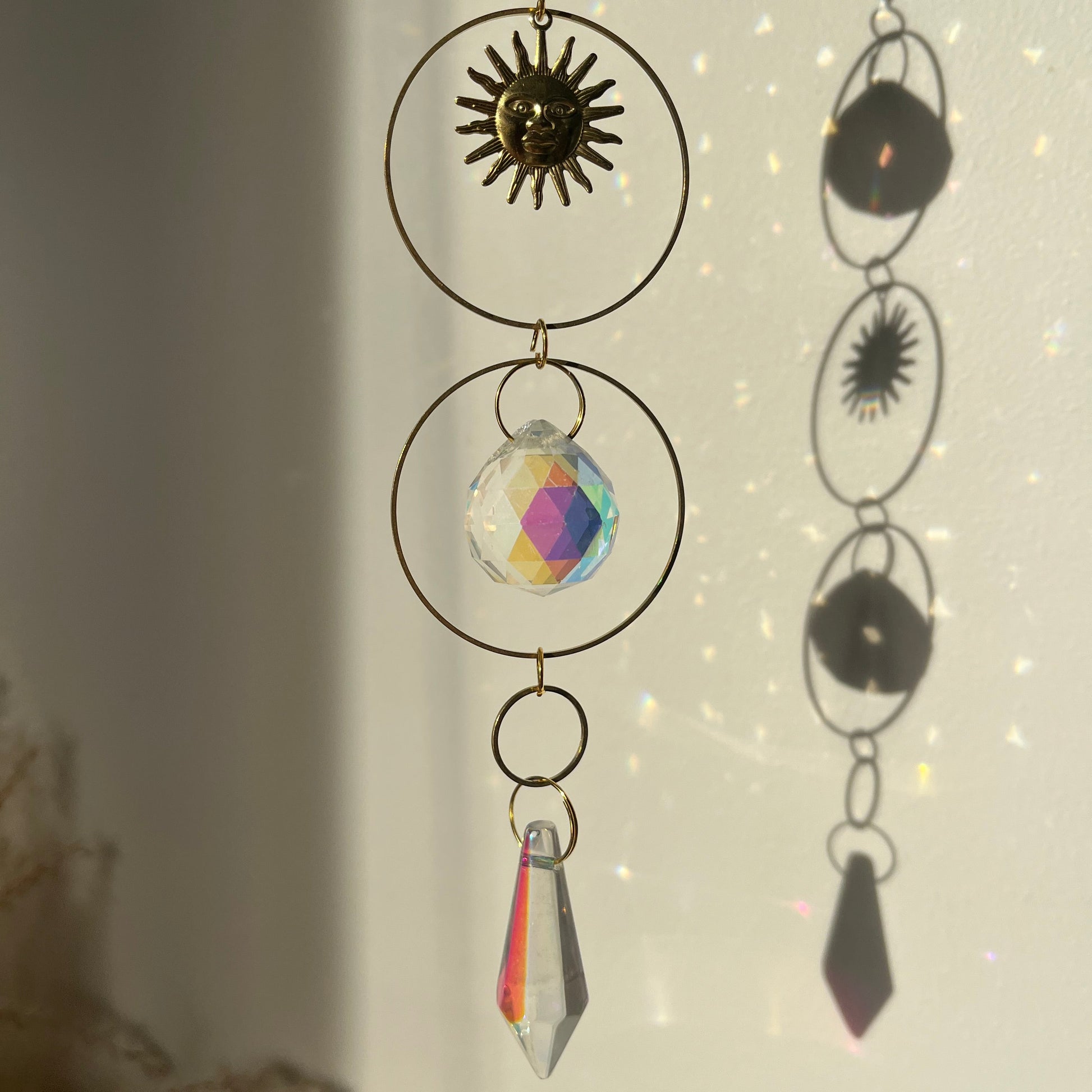 Decorative hanging with geometric shapes and crystals against a light background