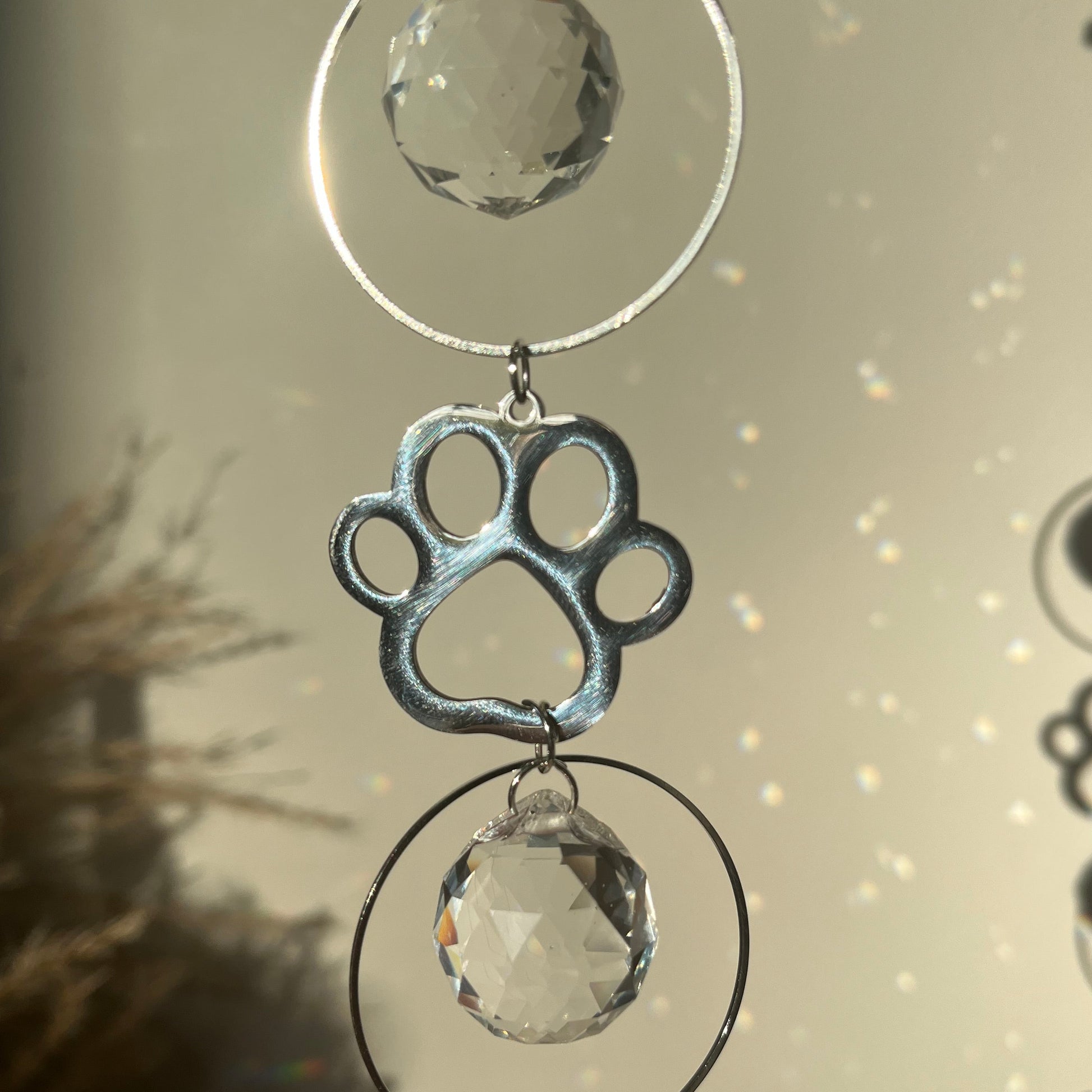 Decorative hanging with crystal-like elements and a paw print design on a neutral background