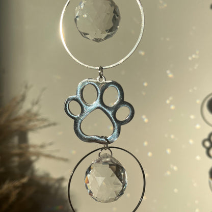 Decorative hanging with crystal-like elements and a paw print design on a neutral background