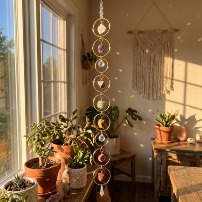Hanging crystal chime in a sunlit room with plants and macrame wall art.