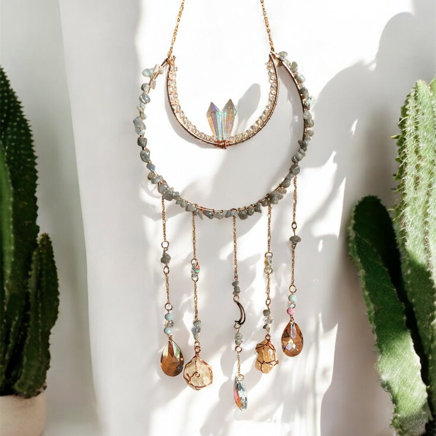 Decorative suncatcher with gemstones in front of a cactus plant