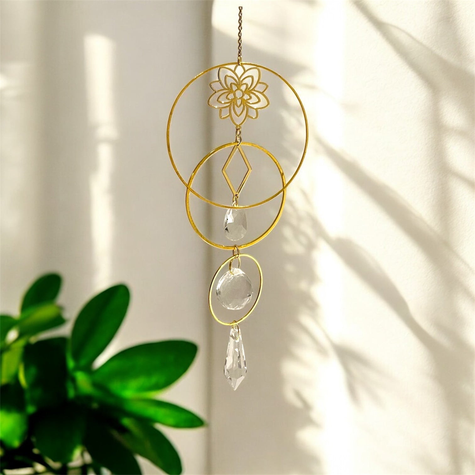 Decorative hanging ornament with gold circular design and clear crystals on a light background