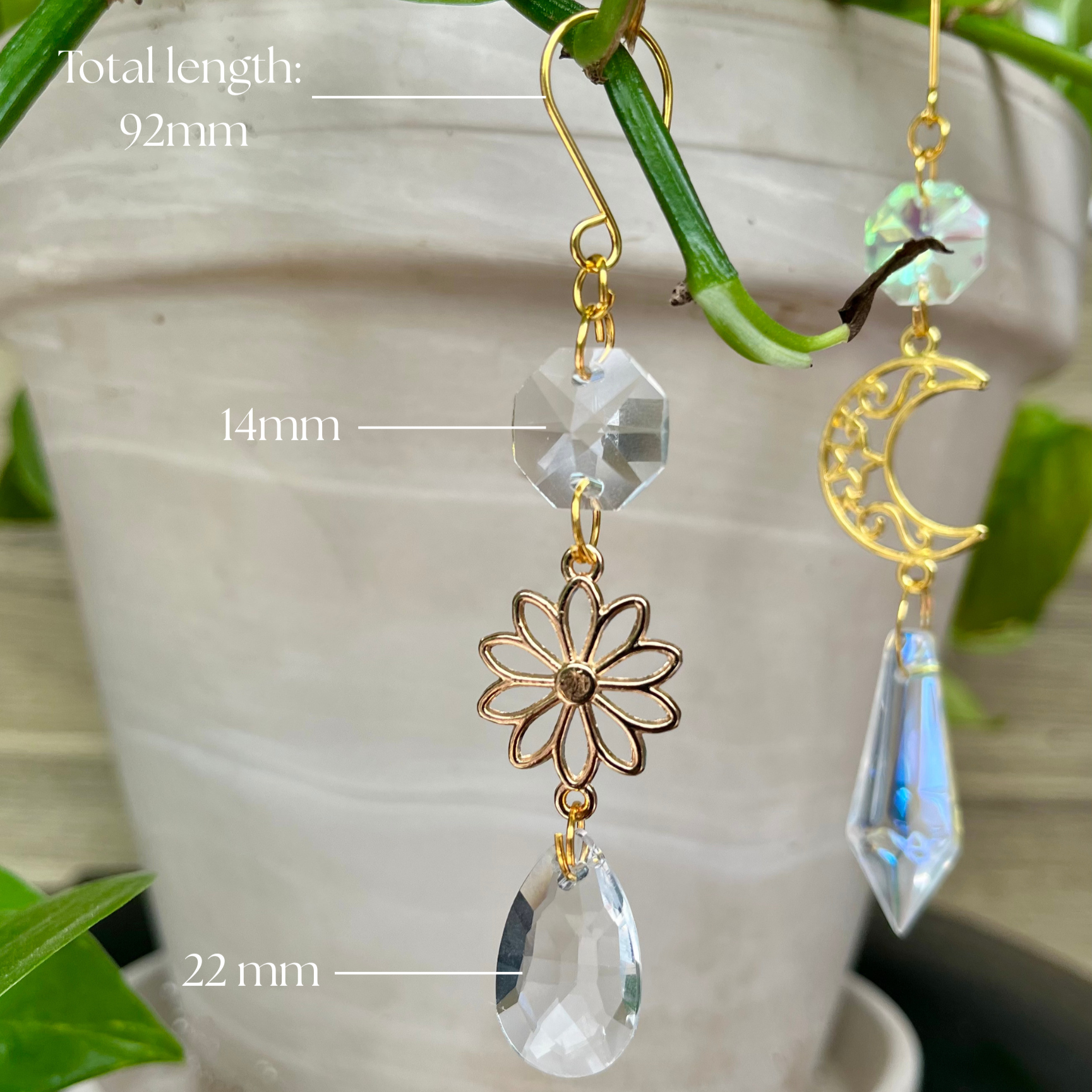 Gold and crystal earrings with measurements against a plant background