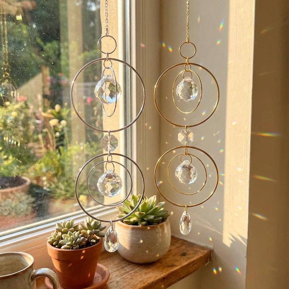Decorative hanging crystal chandelier on a windowsill with plants and a cup.