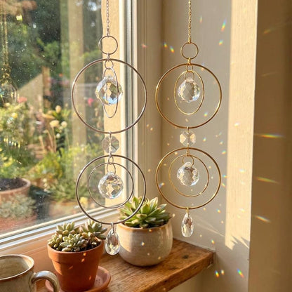 Decorative hanging crystal chandelier on a windowsill with plants and a cup.