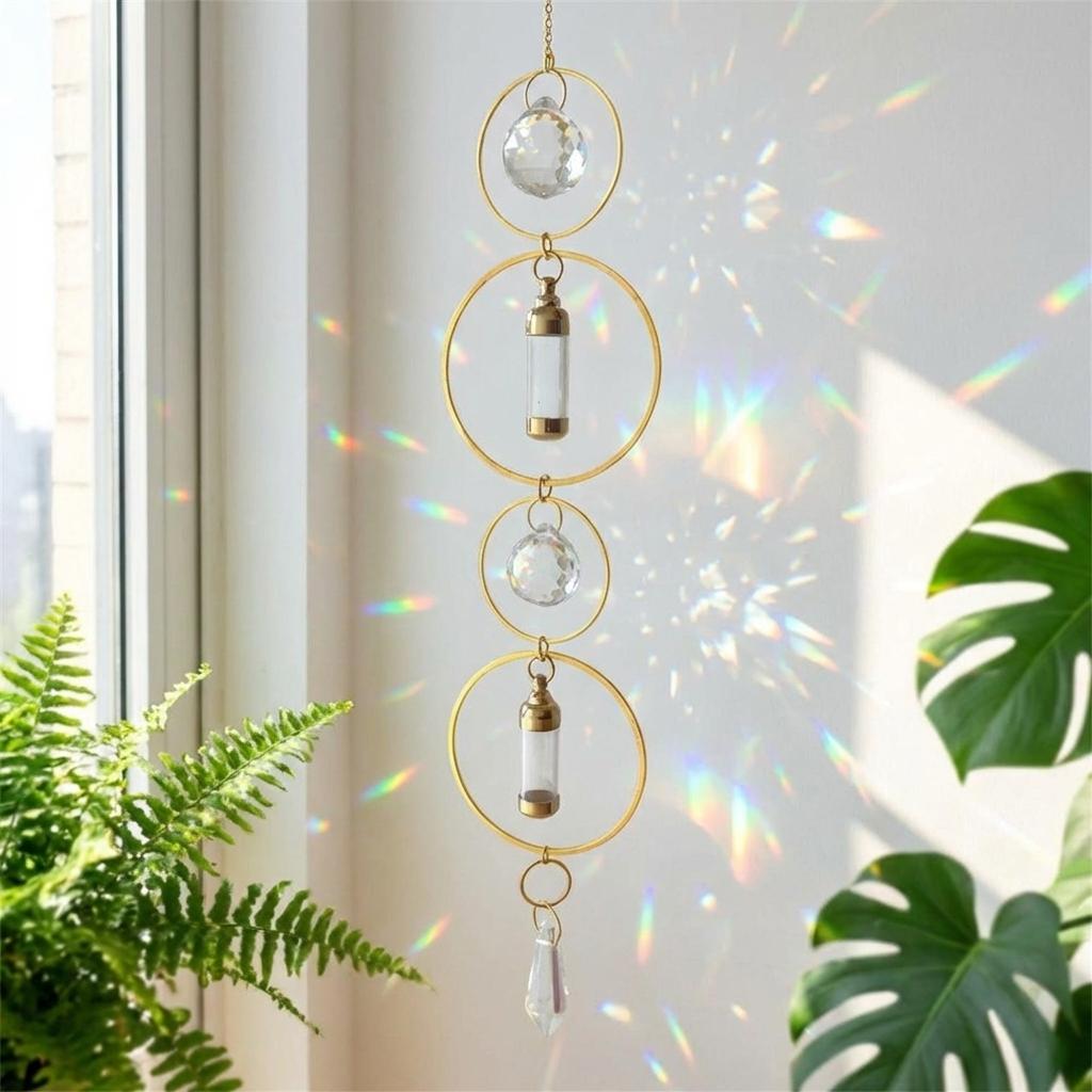 Decorative hanging crystal with gold loops in front of a window with sunlight filtering through.