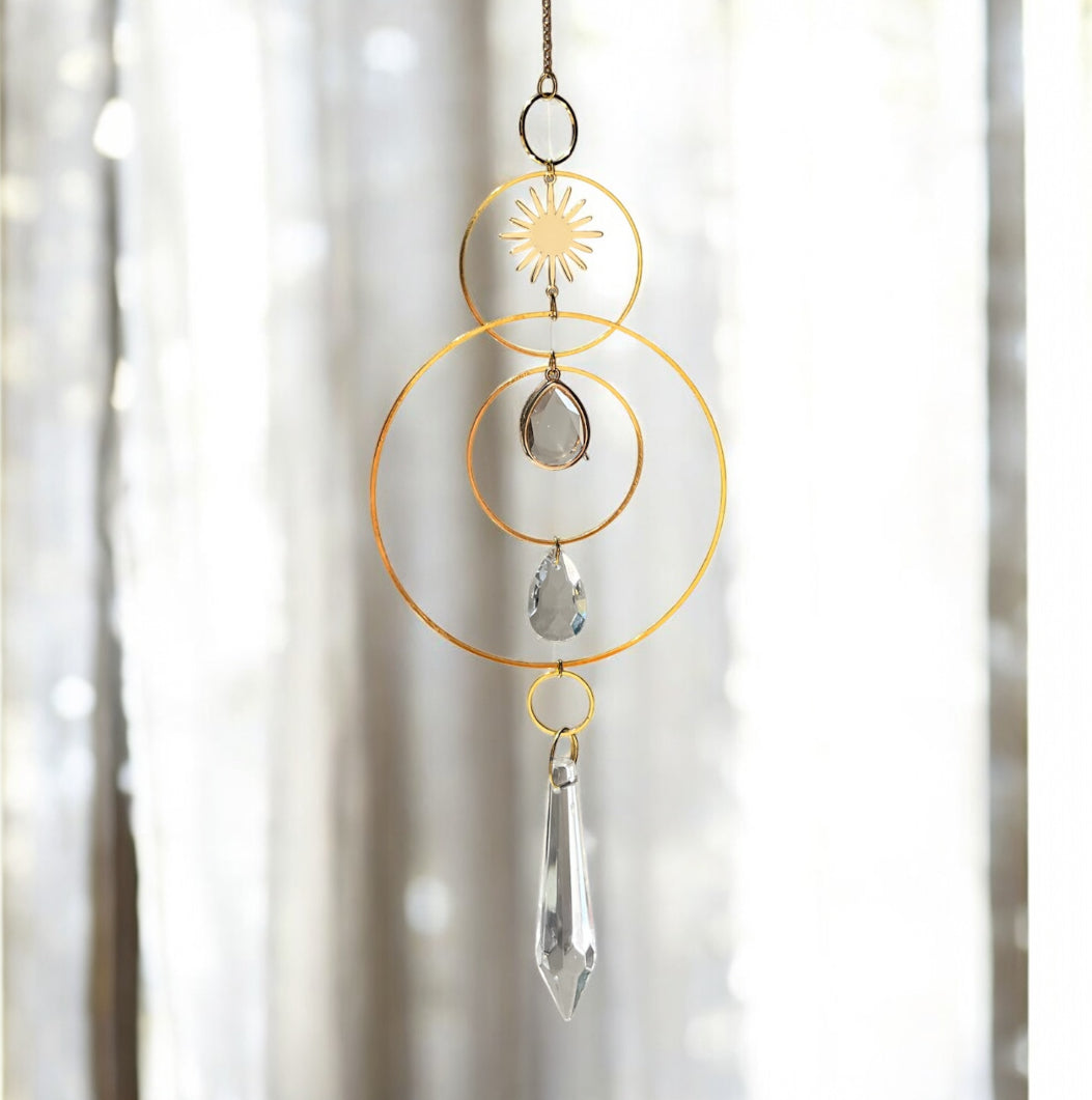 Decorative hanging crystal with gold loops and clear crystals against a blurred background