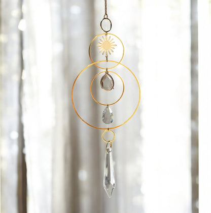 Decorative hanging crystal with gold loops and clear crystals against a blurred background