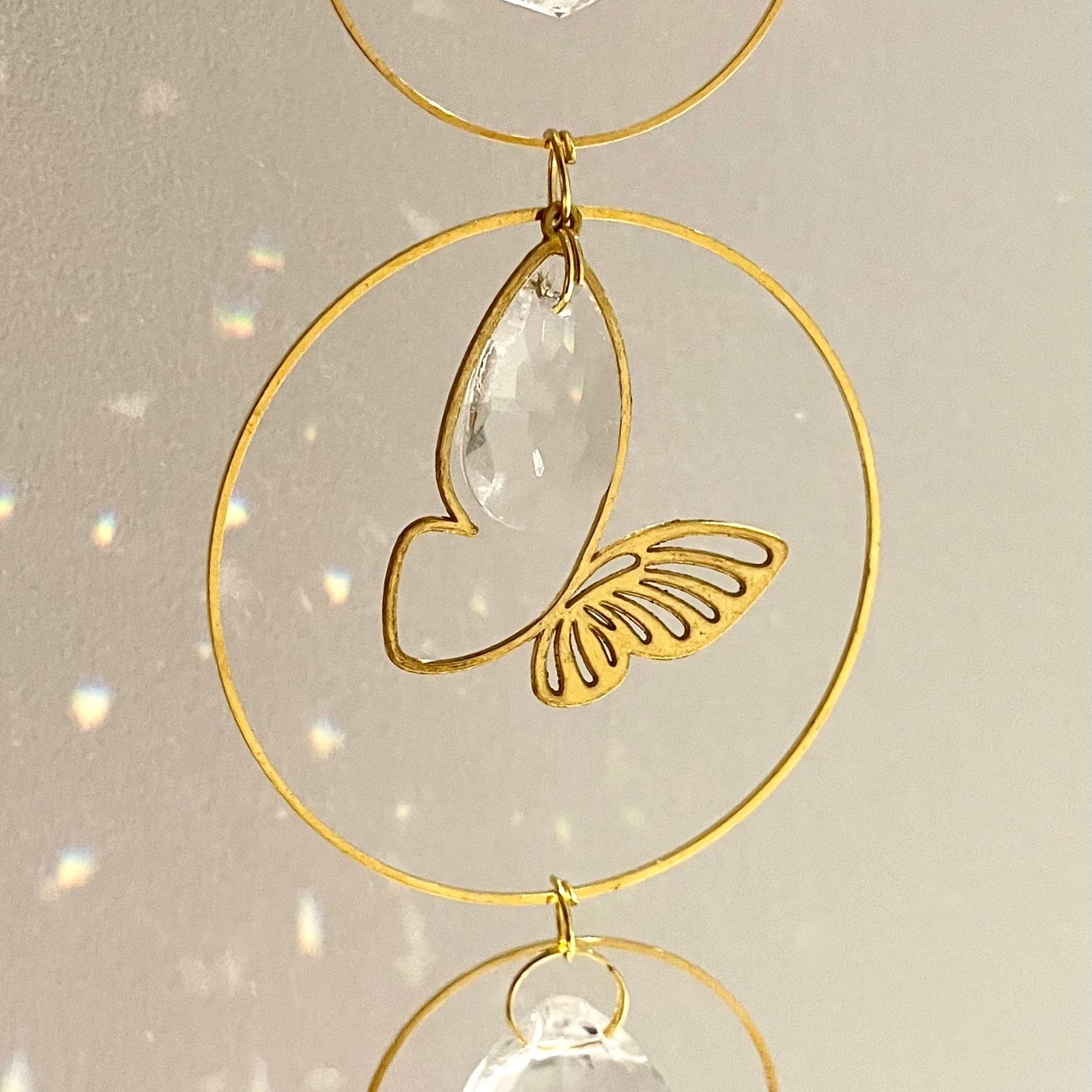 Decorative hanging with gold loops and clear crystals on a light background