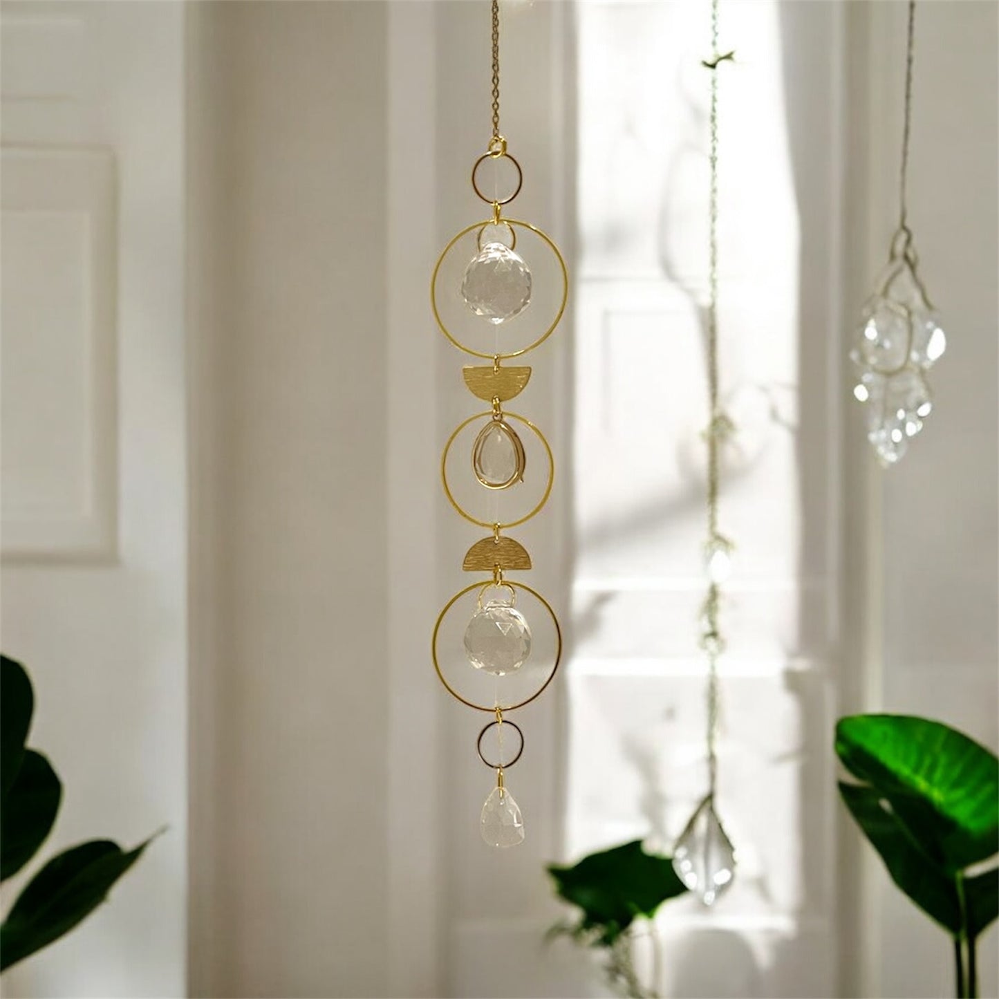 Decorative hanging chain with gold rings and clear crystals in a bright room.