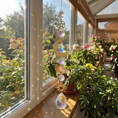 Decorative crystal suncatcher with celestial design hanging in front of a window with plants.