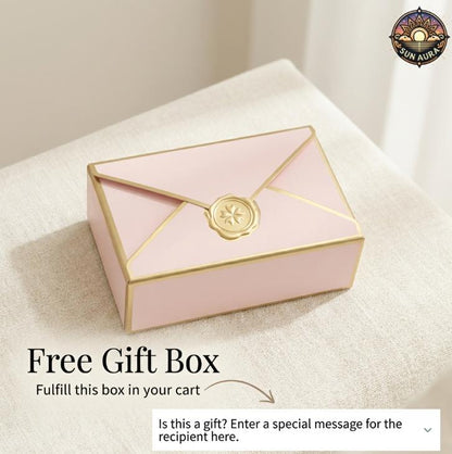 Pink gift box with gold accents on a beige surface, featuring a brand logo in the corner.