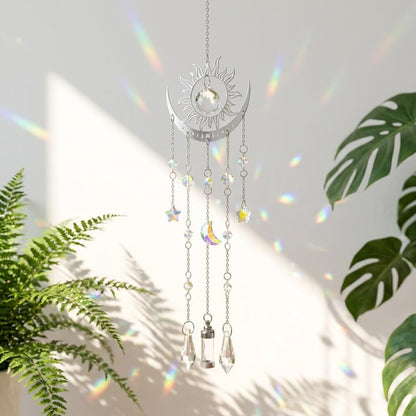 Decorative hanging sun and moon ornament with crystals on a white background with plant elements.