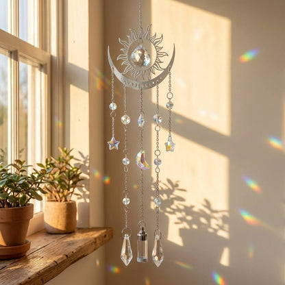 Decorative hanging crystal with sun, moon, and star designs in a sunlit room.