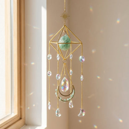 Decorative hanging crystal ornament with geometric design in front of a window.