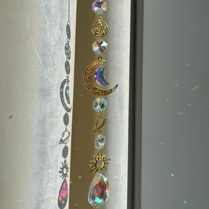 Decorative hanging charm with celestial elements on a plain background
